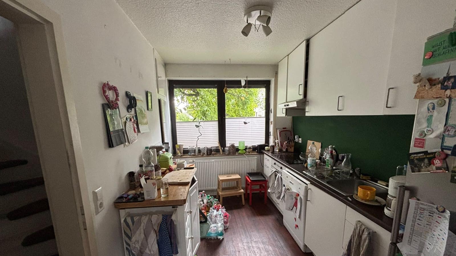 Küche mit Fenster, grüner Rückwand und Holzboden