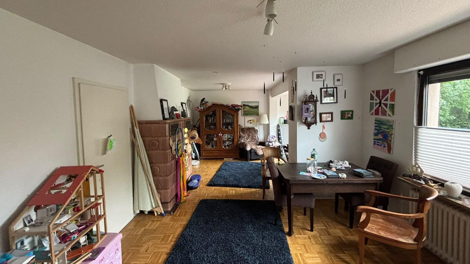 Bewohntes Wohnzimmer mit Regal, Esstisch und Sofa